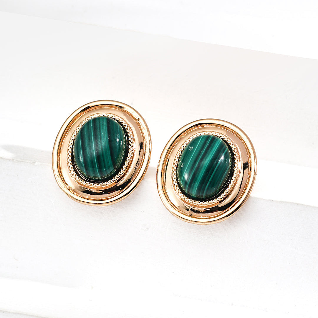 Gold earrings with green gemstones on a white background