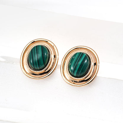 Gold earrings with green gemstones on a white background