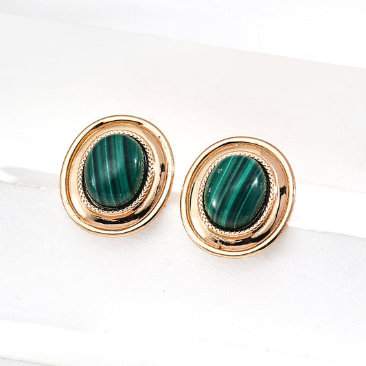 Gold earrings with green gemstones on a white background