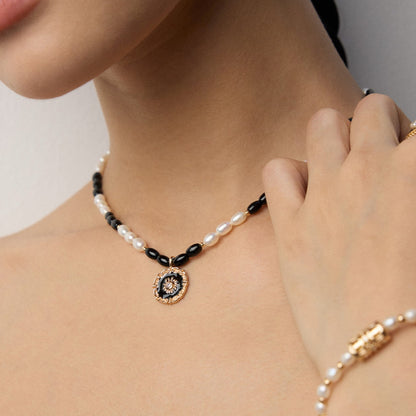 Solara S925 gold-plated necklace with natural pearl, black onyx beads, and enamel sun pendant on light background